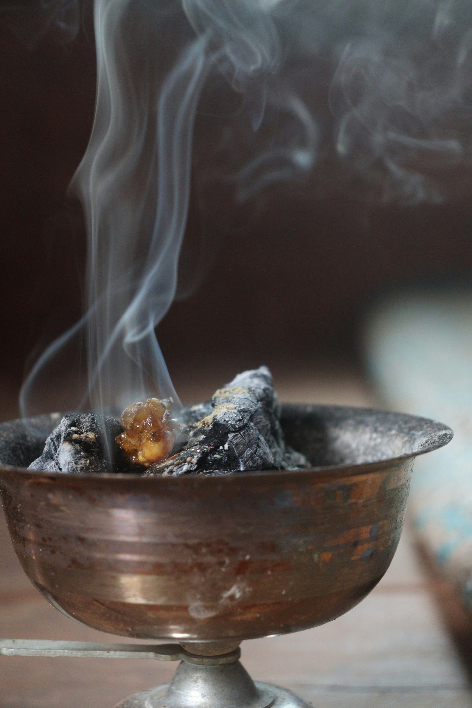 Incense burning in a bowl on the alter with a lit candle in the background